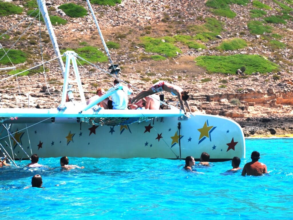 Person springt von Boot ins türkisfarbene Meer