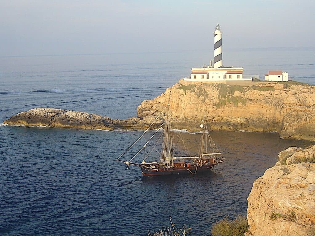 Segelboot vor Leuchtturm am Meer