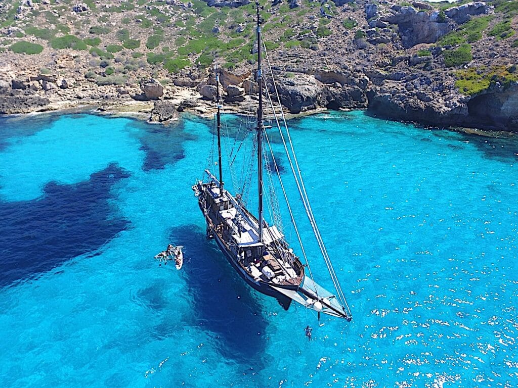 Segelschiff in türkisfarbenem Wasser, Küste